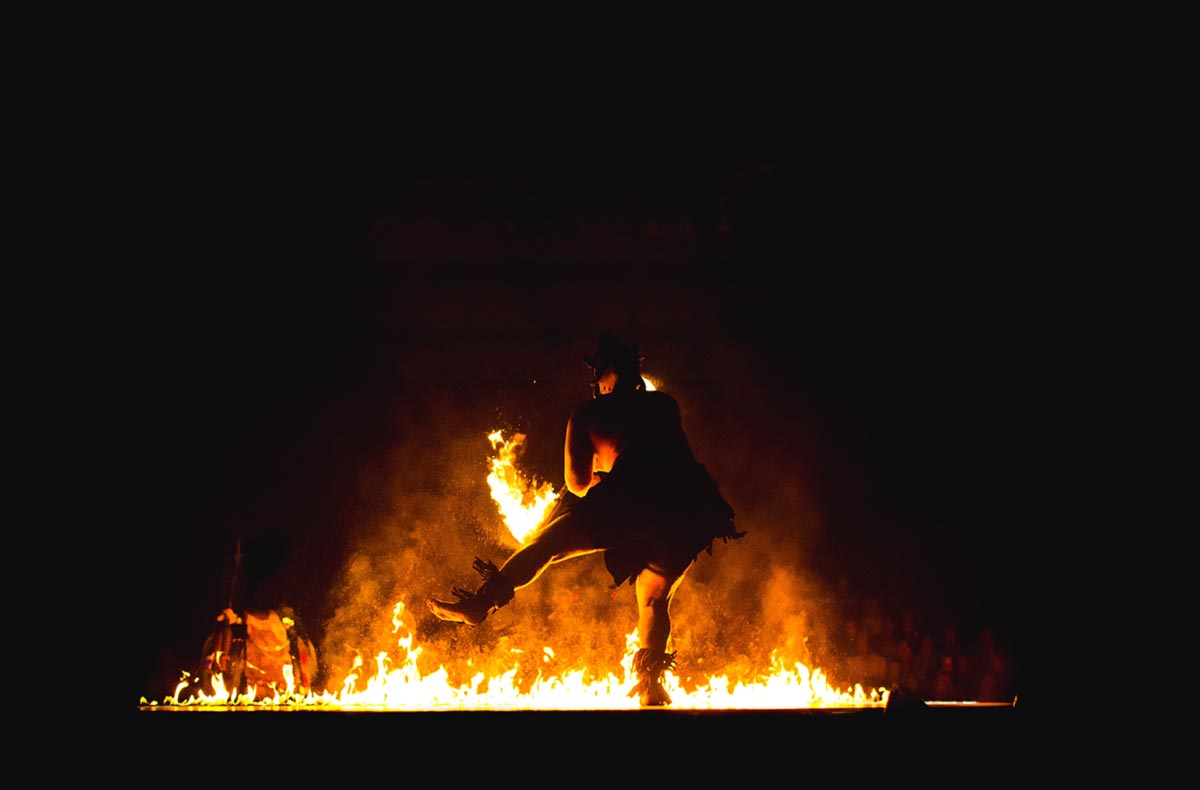 Ein Mann tanzt vor einem Freudenfeuer an Beltane