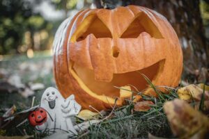Geschnitzter Halloween-Kürbis auf einer herbstlichen Wiese