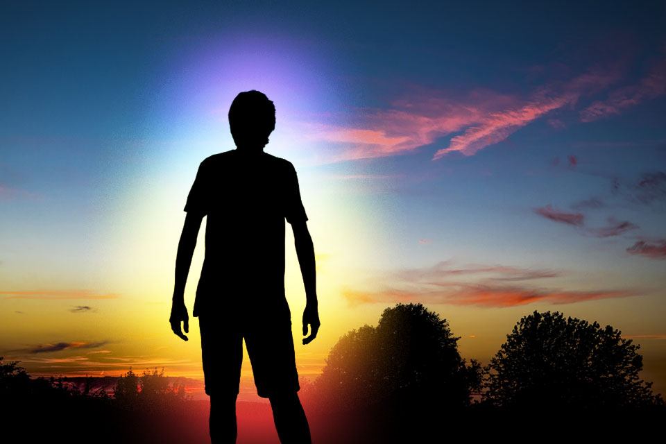 Silhouette einer Person im Sonnenuntergang mit grafischer Visualisierung einer Aura mit den Farben der Chakren.