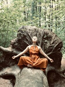 Swanje Vanessa Sagebiel meditiert im Wald an einer Baumwurzel